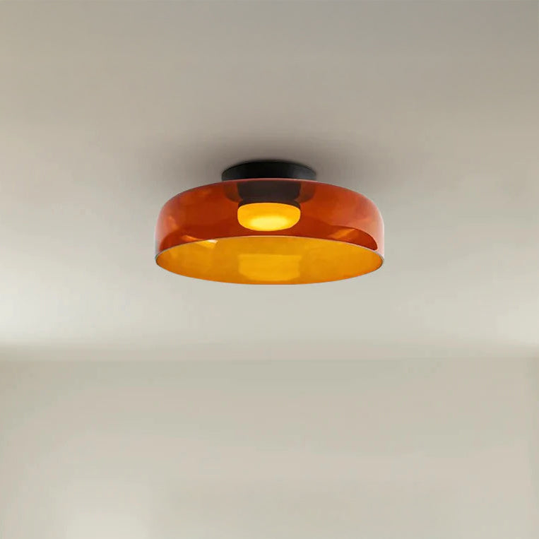 Wide amber circular ceiling lamp with a translucent acrylic shade and warm light on a clean white ceiling.