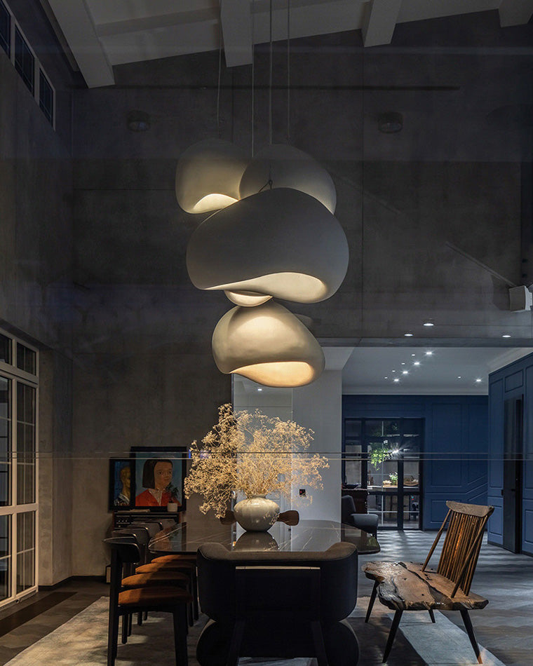 A warm dining room chandelier cluster creates an intimate focal point against dark walls and natural wood furniture.