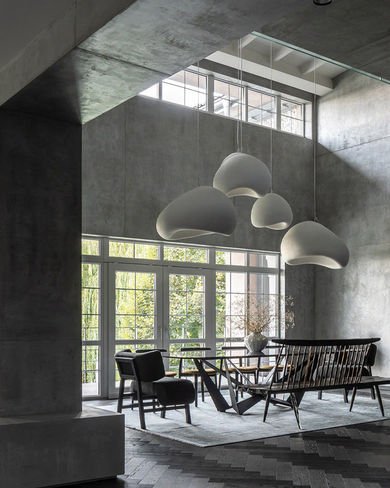 A white dining room chandelier cluster softens the raw concrete surfaces of a loft-style dining area.