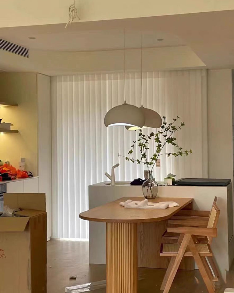 Two sculptural shades form a balanced dining room chandelier above a round wood table.