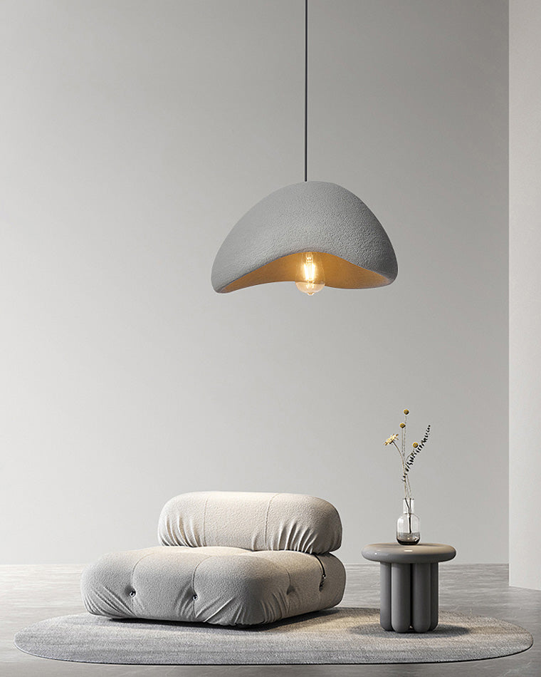 A single grey resin dome pendant hangs above a minimalist lounge chair, creating a quiet reading corner.