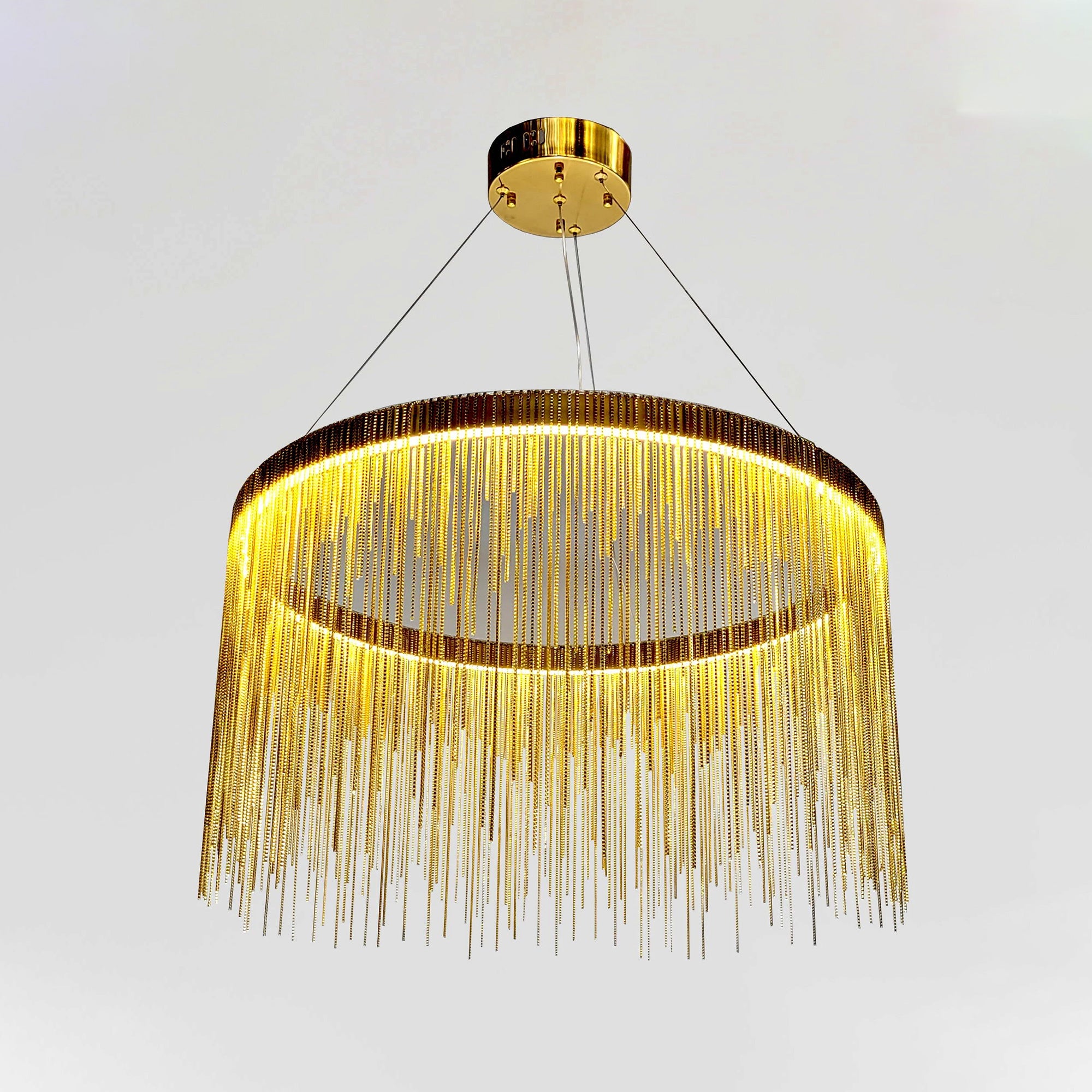 Low-angle close view of the gold 20-inch fringe chandelier, emphasizing the illuminated ring and richly layered metal-chain curtain.