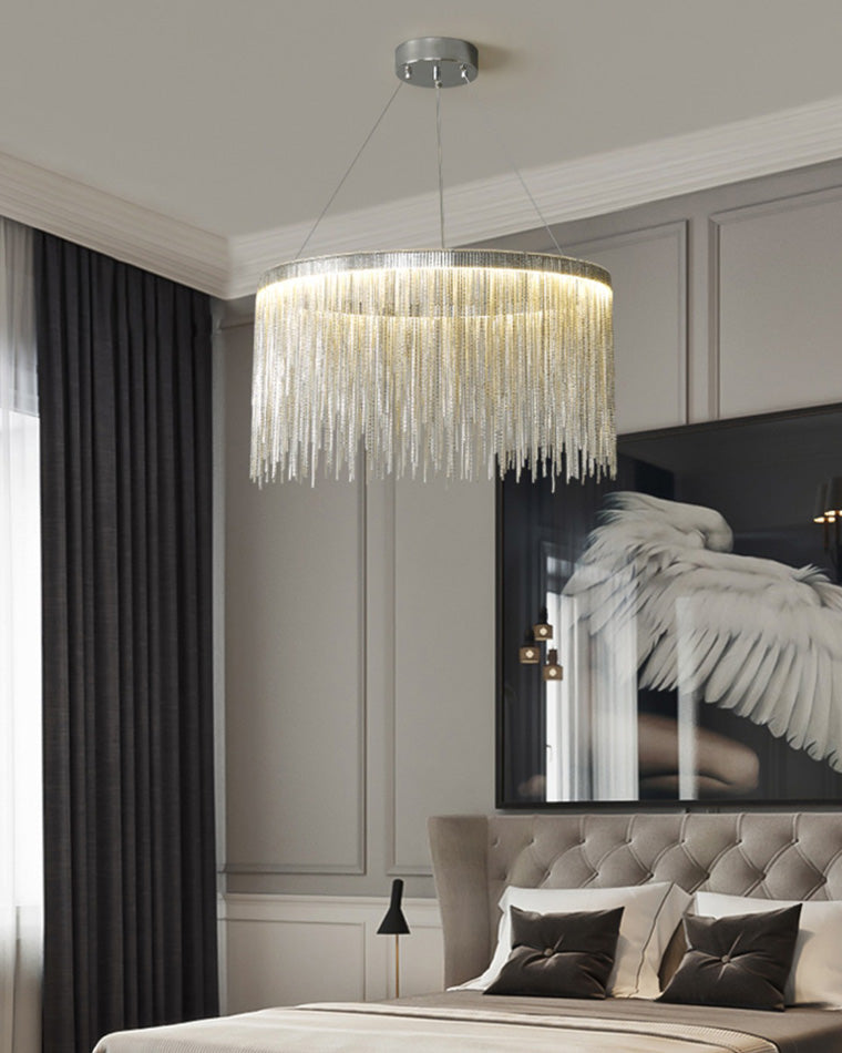 Silver chandelier poised above a bed with dramatic wing-inspired wall art, giving the bedroom atmospheric light and a refined theatrical finish.