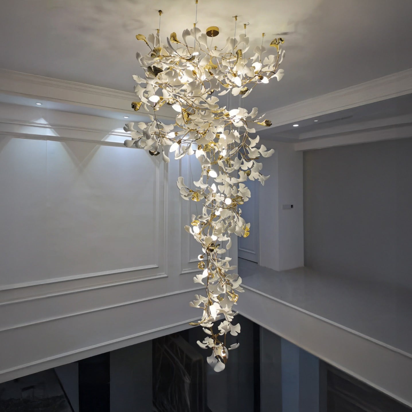 2 story foyer chandelier with white ceramic ginkgo leaves cascading through an open interior void.