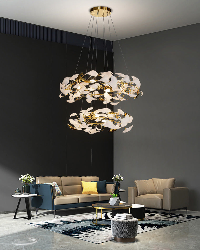 Two-tier circular ginkgo chandelier casting a warm sculptural glow in a dark-walled living room.