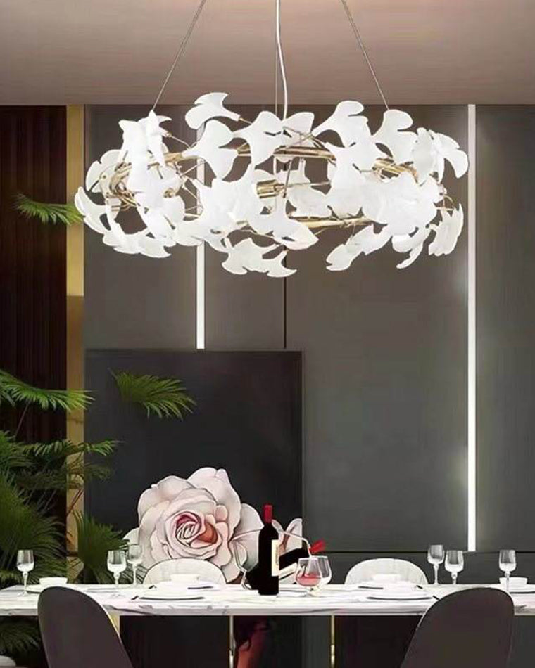 White dining room chandelier above a dark contemporary table, its warm bulbs and ceramic leaves standing out against moody walls.