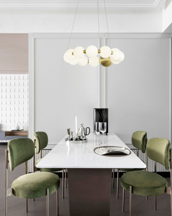 This pearl-ring design shows how statement dining room chandeliers can center a table, pairing luminous LED globes with a polished gold focal sphere.