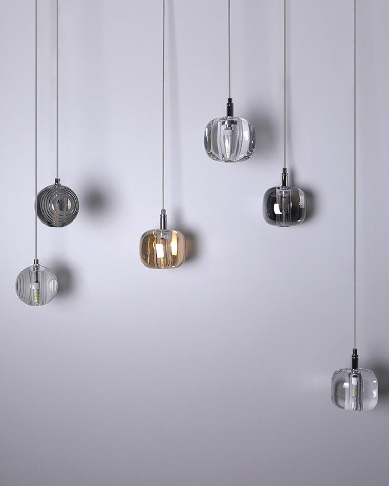 Amber, smoked, and clear pendants arranged asymmetrically on the waterfall glass chandelier, emphasizing the mixed-glass palette and relaxed vertical spacing.