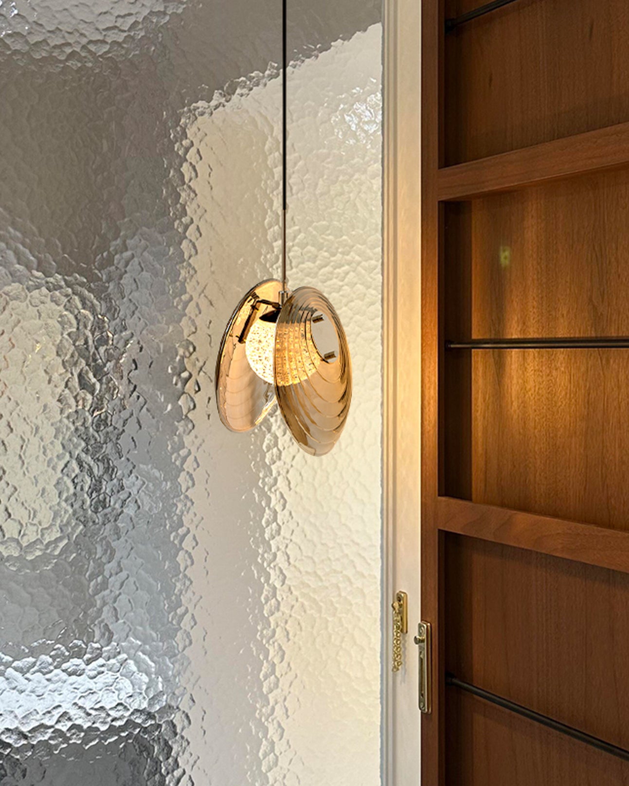Smoke grey living room pendant light with rippled glass discs glowing above a side table in a cozy lounge setting.