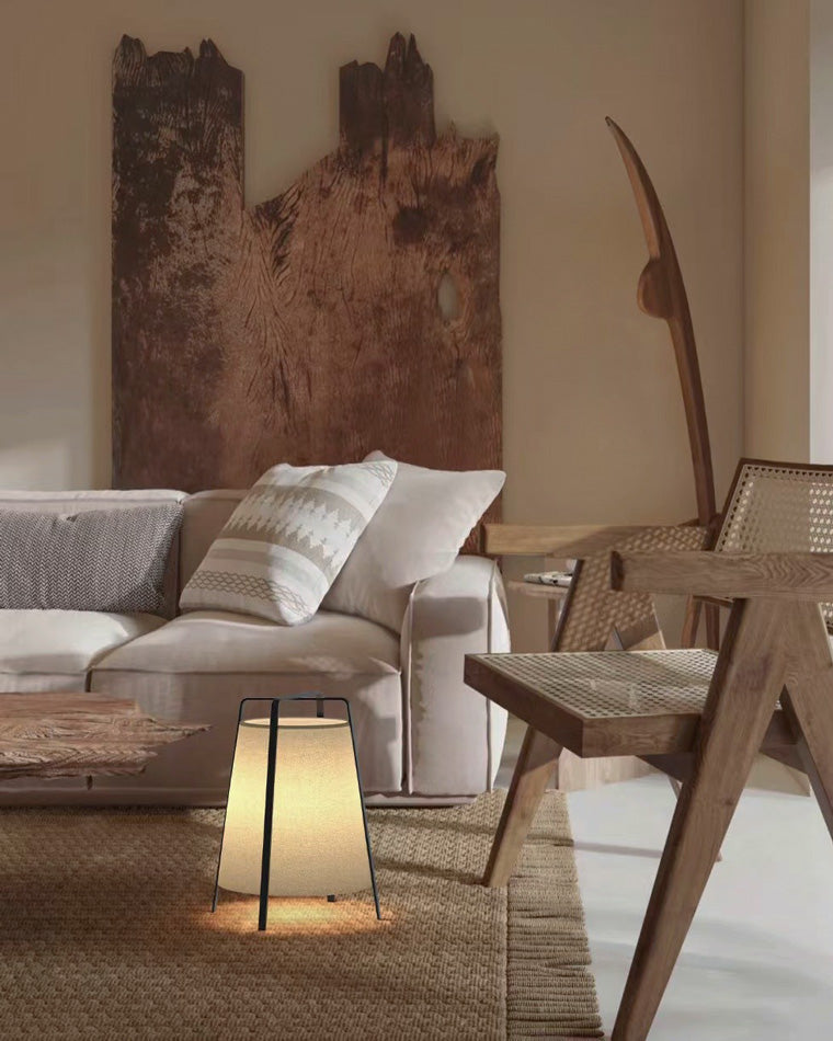 Small lantern-style floor lamp adding a warm glow beside a sofa and woven rug.