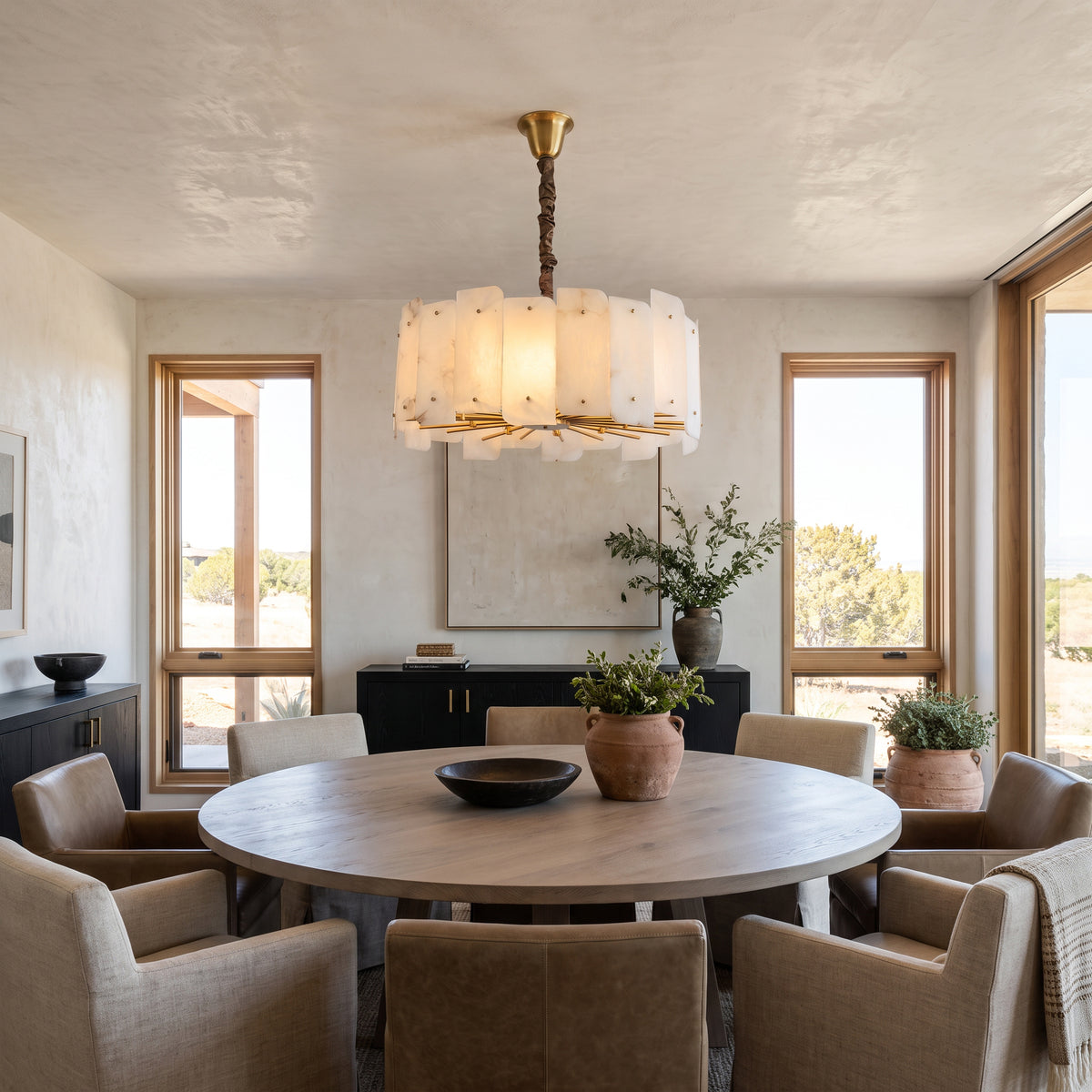 WOMO WM2391 glowing alabaster chandelier above a round dining table with upholstered chairs.