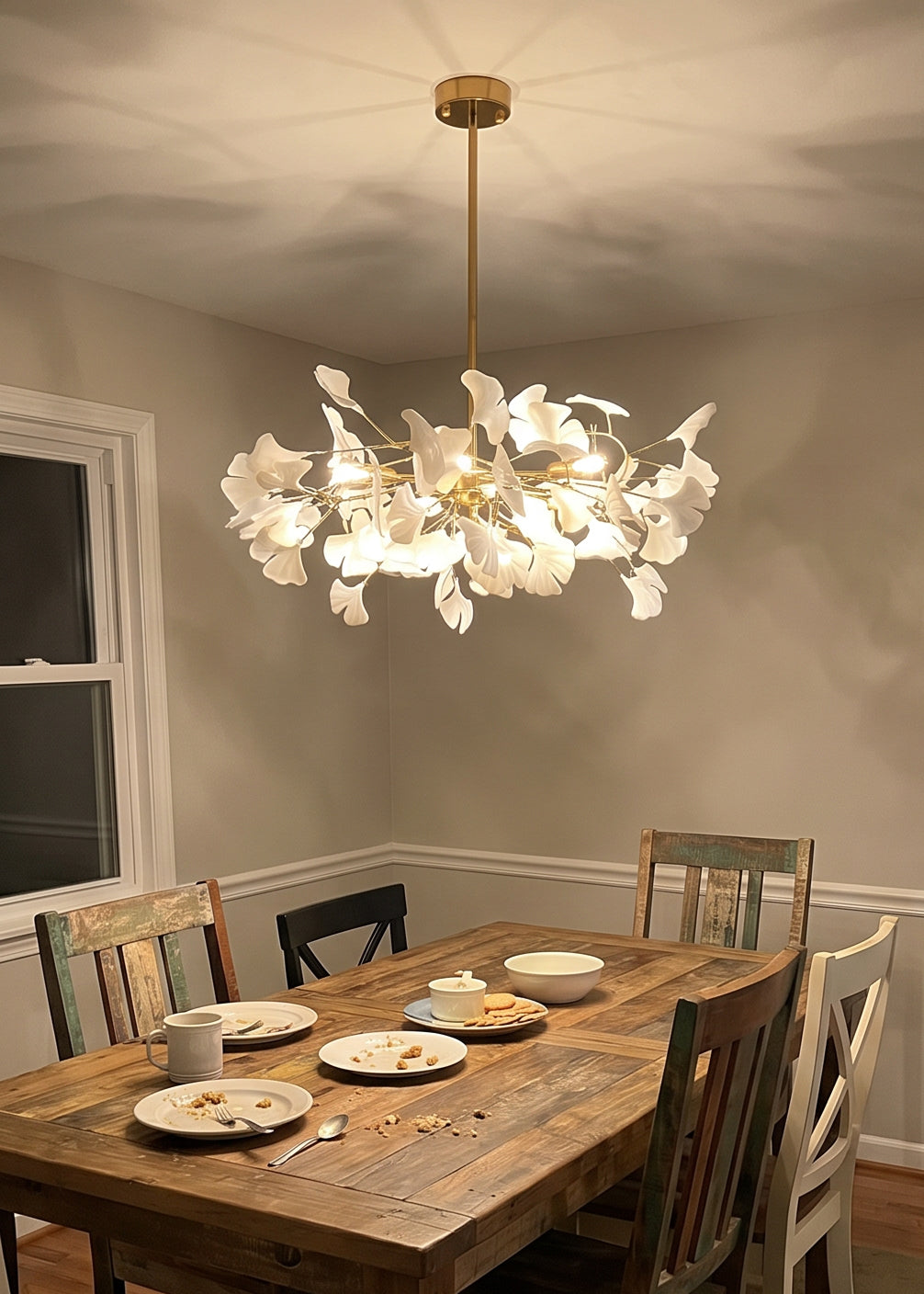Glowing white leaf chandelier for dining room suspended above a wood dining table