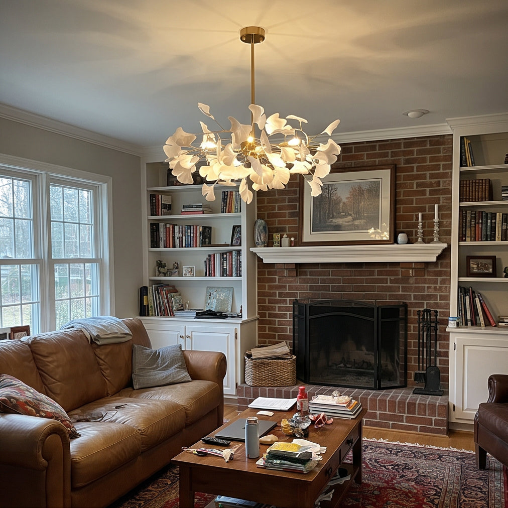 Decorative gold branch chandelier with white ginkgo leaves above a cozy fireplace seating area