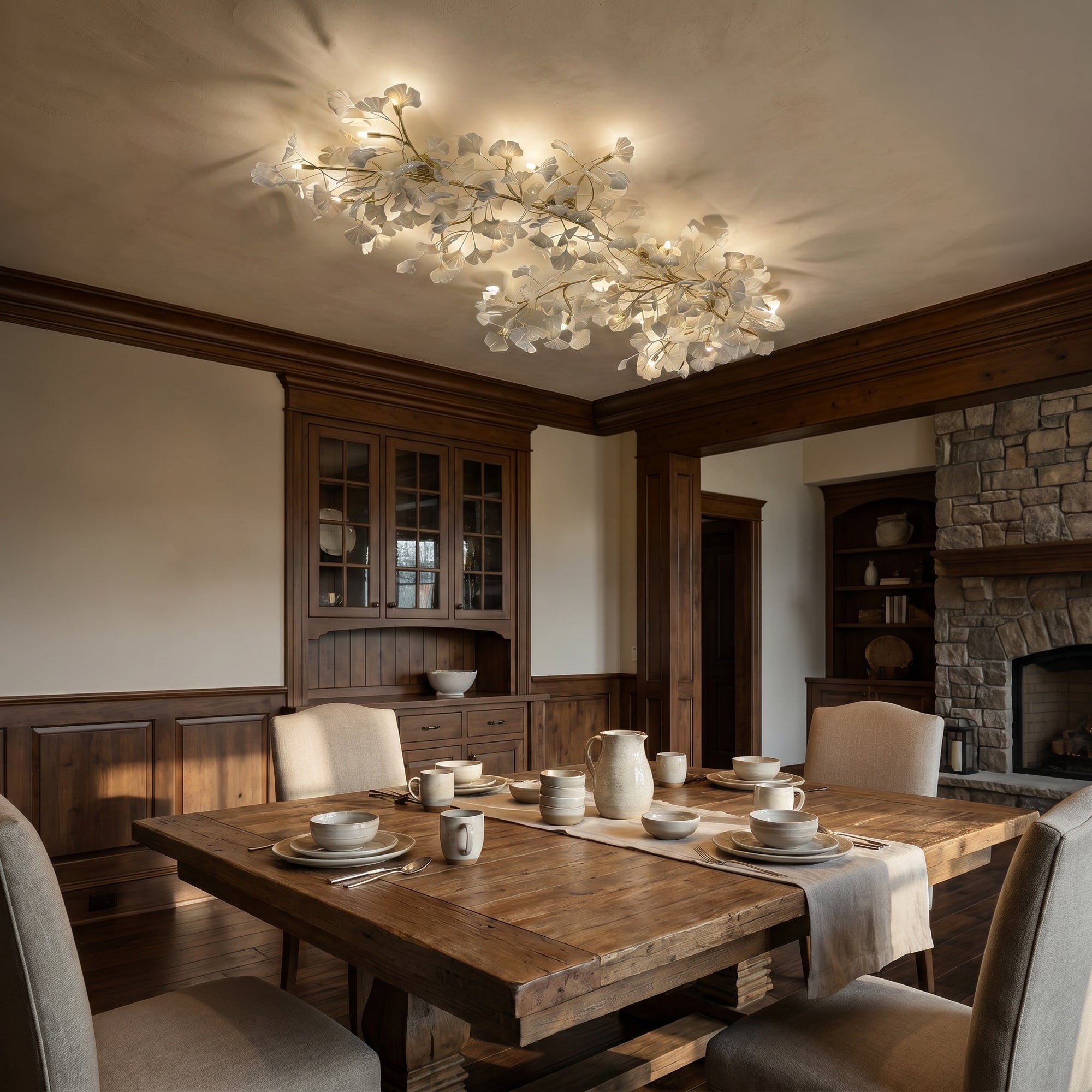 White ceramic ginkgo leaf ceiling light with gold branches glowing above a warm wood dining room.