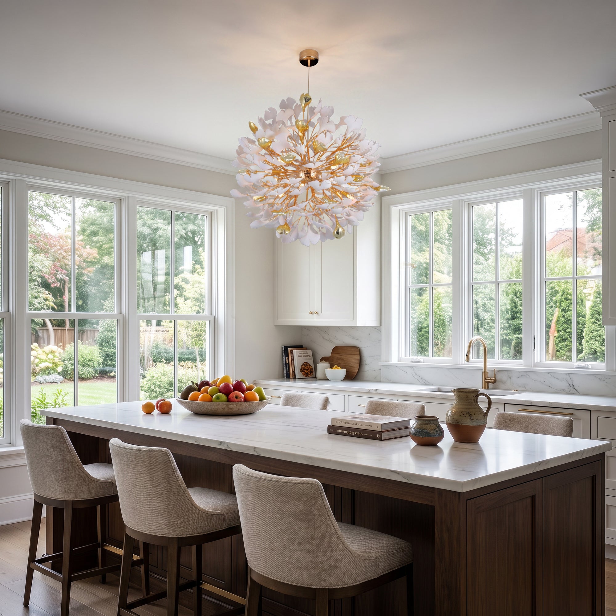 An elegant bright kitchen with a dark wood island and white marble countertop; a large white and gold chandelier with petal-like shades hangs above the island.