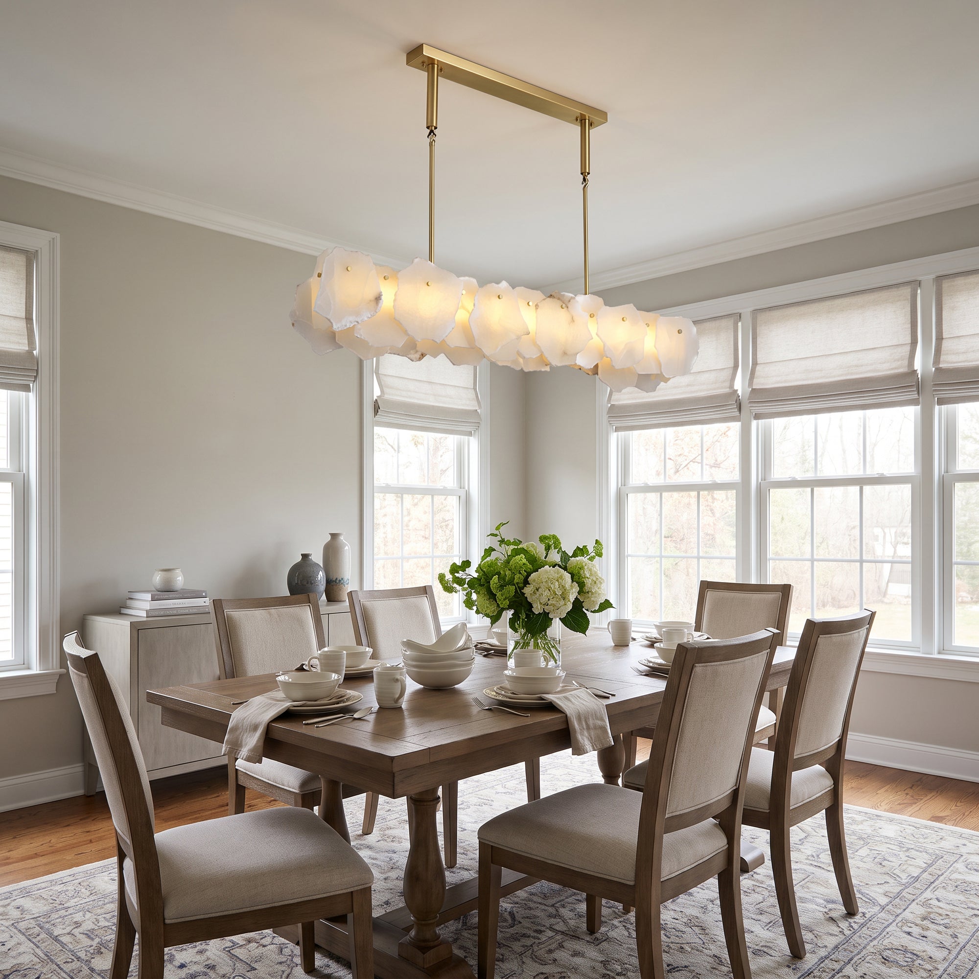 Modern linear alabaster chandelier hanging above a dining table, featuring translucent stone shades and a rectangular frame in a bright contemporary dining room
