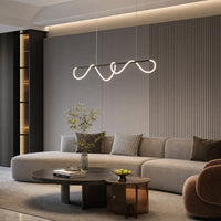 Matte-black linear chandelier with illuminated looping silicone suspended above a curved sofa in a dark contemporary living room.
