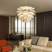 White pinecone pendant light hanging over a cozy living room, adding soft warm light and sculptural style.