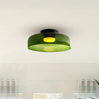 Wide green low profile LED ceiling light with a translucent round shade and warm center glow above a softly lit room.