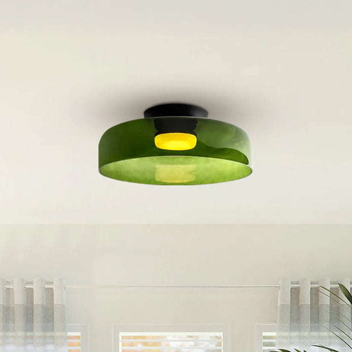 Wide green low profile LED ceiling light with a translucent round shade and warm center glow above a softly lit room.