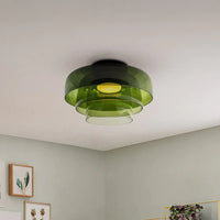 Three-tier green circular ceiling light with translucent layered shades in a calm neutral interior.