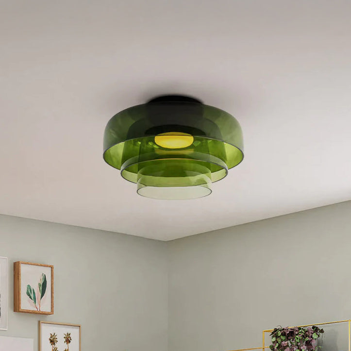 Three-tier green circular ceiling light with translucent layered shades in a calm neutral interior.