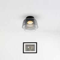 Two-tier smoked acrylic contemporary ceiling light above framed wall art in a bright minimalist room.