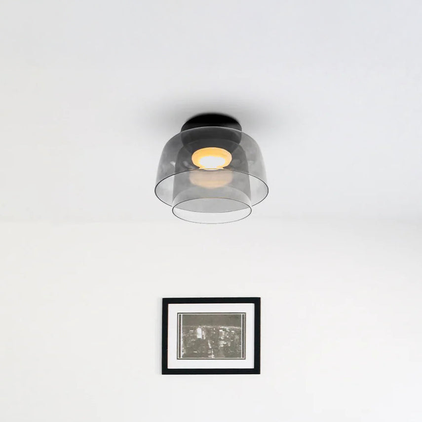 Two-tier smoked acrylic contemporary ceiling light above framed wall art in a bright minimalist room.