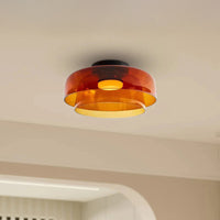 Amber acrylic flush mount drum light fixture with two overlapping shades in a warm beige interior.