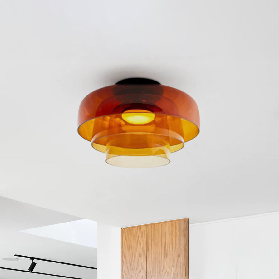 Three-tier amber circular ceiling light fixture with translucent layered shades in a bright modern interior.