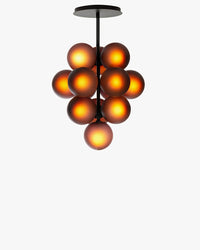 Front view of the illuminated grape chandelier with warm light glowing through purple glass globes.