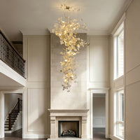 Large foyer chandelier with cascading white ceramic ginkgo leaves suspended above a fireplace in a double-height entry.