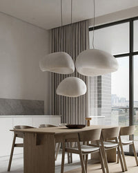 Four rounded shades create a cloud-like dining room chandelier above a table washed in natural daylight.