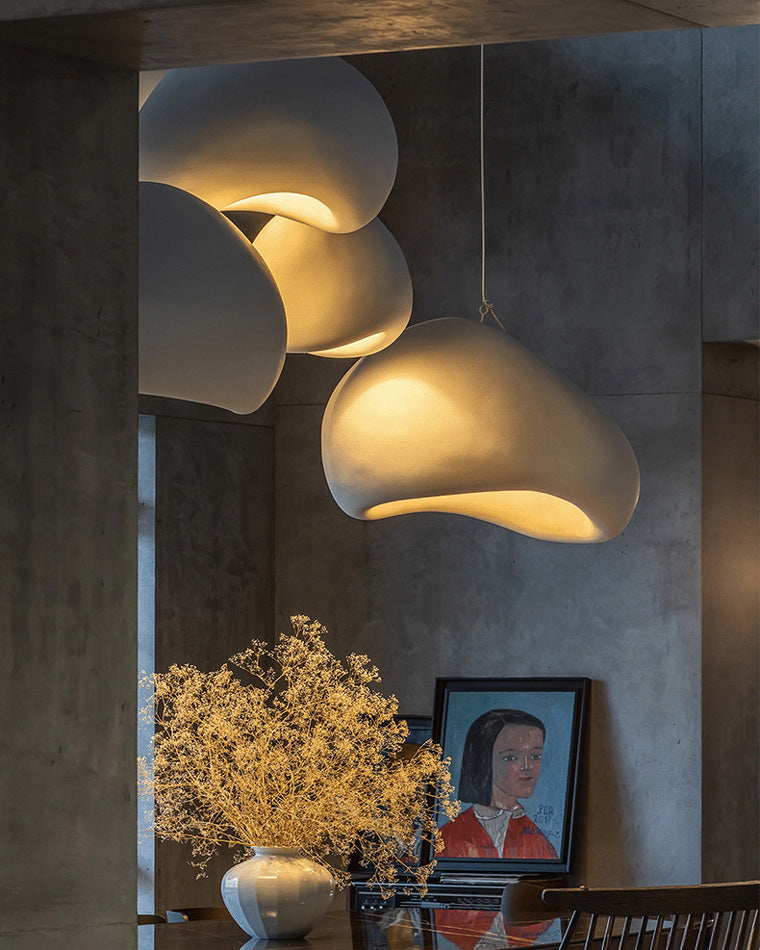 Close-up of overlapping resin shades in a sculptural pendant lighting arrangement, glowing warmly above a console.