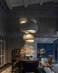 A warm dining room chandelier cluster creates an intimate focal point against dark walls and natural wood furniture.