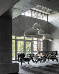 A white dining room chandelier cluster softens the raw concrete surfaces of a loft-style dining area.