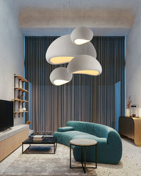 Sculptural pendant lighting adds soft pools of light above a teal sofa in a modern living room.