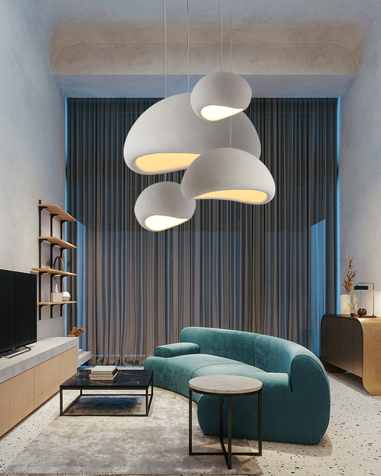 Sculptural pendant lighting adds soft pools of light above a teal sofa in a modern living room.