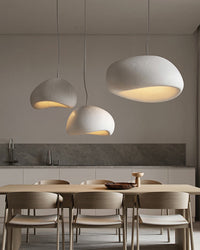 Three rounded resin shades form balanced pendant lighting above a pale wood dining table.
