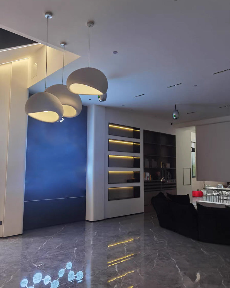 Three organic pendants create warm pendant lighting against a saturated blue accent wall.