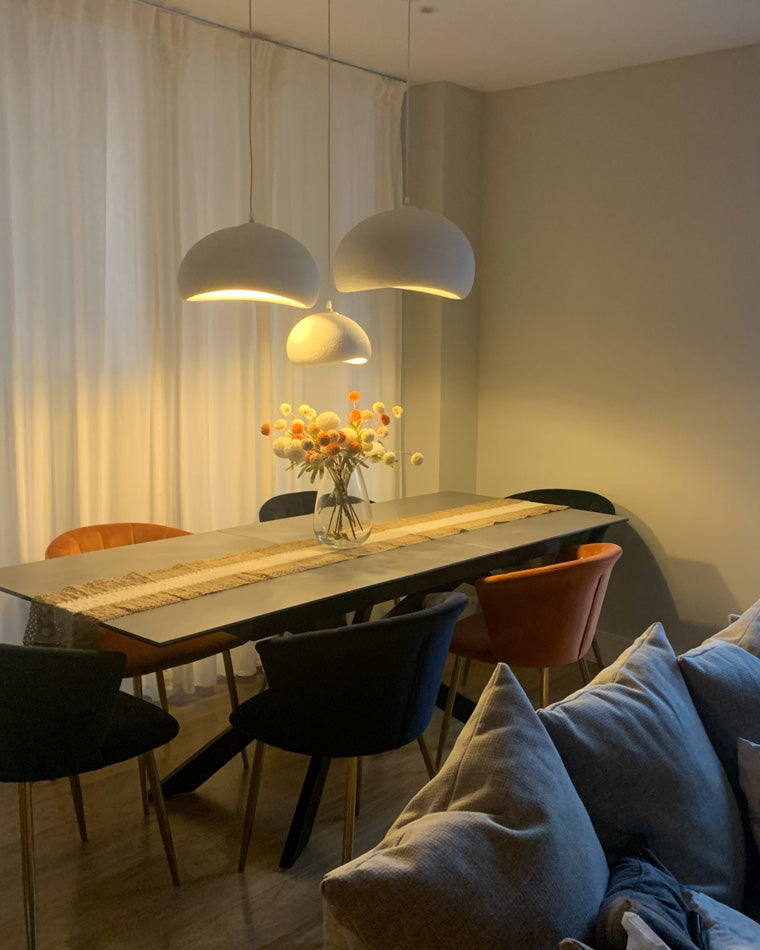 A sculptural dining room chandelier washes a wood table and floral centerpiece with intimate warm light.
