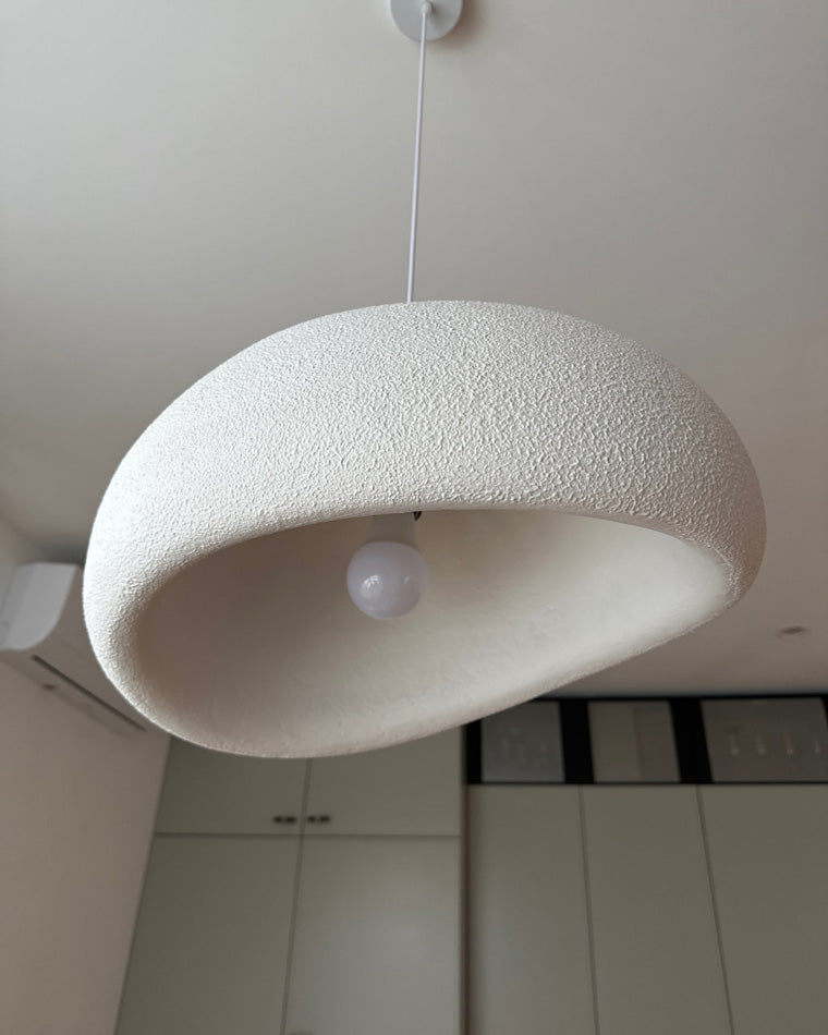 Underside close-up of a white textured resin pendant showing the curved opening and central E27 bulb.