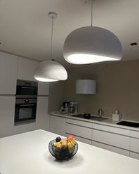 Two white dome pendant lights provide focused illumination above a minimalist kitchen island.