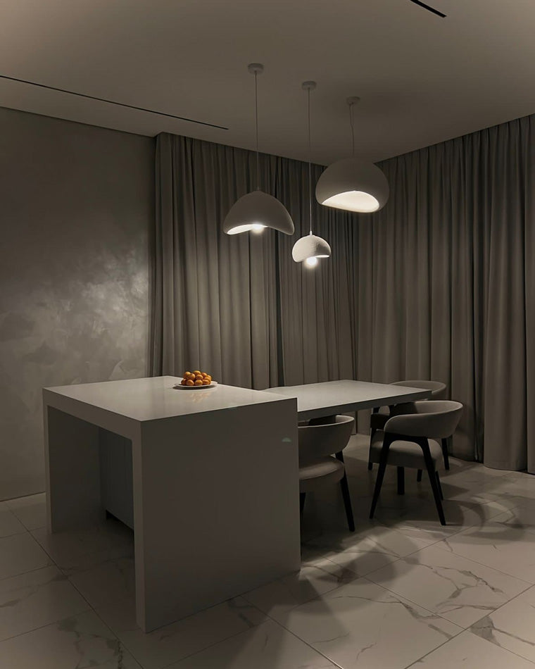 Three organic pendant lights float above a grey kitchen island and adjacent dining bench.