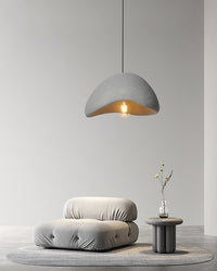 A single grey resin dome pendant hangs above a minimalist lounge chair, creating a quiet reading corner.
