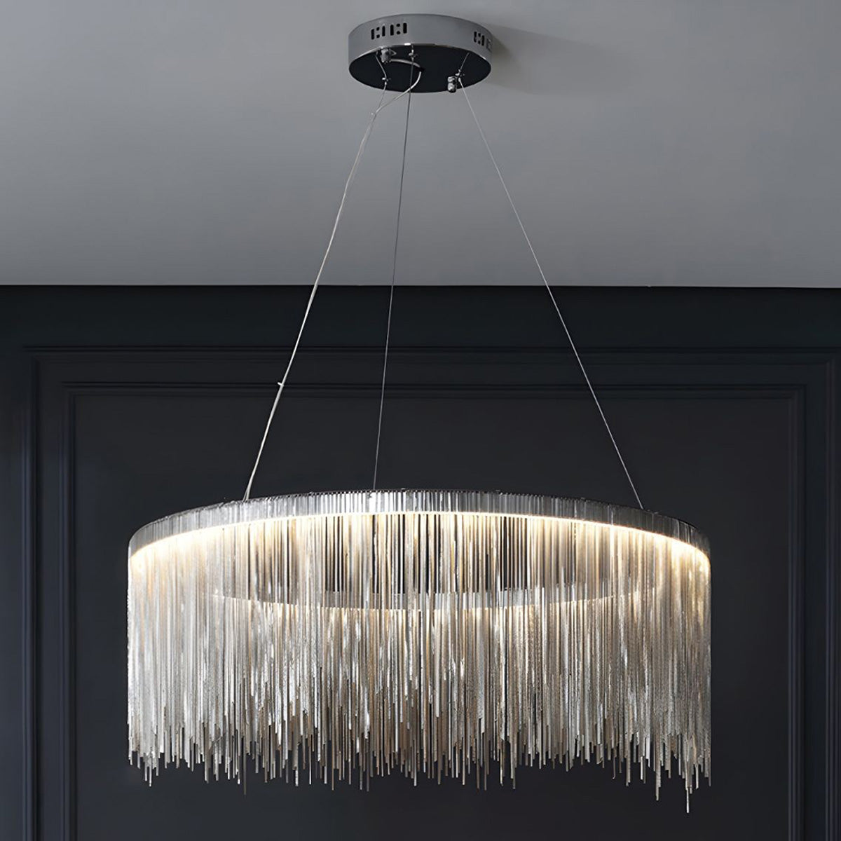 Illuminated silver 24-inch chandelier against a dark paneled wall, demonstrating how the mid-size design delivers statement light without overwhelming the room.