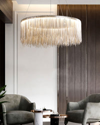 Silver chain chandelier illuminating two lounge chairs, creating a welcoming pool of light while its rounded form brings symmetry to the dark wood interior.