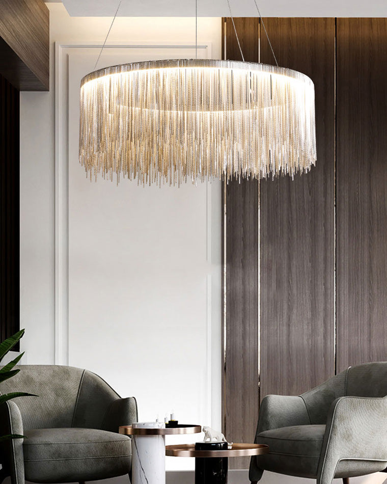 Silver chain chandelier illuminating two lounge chairs, creating a welcoming pool of light while its rounded form brings symmetry to the dark wood interior.