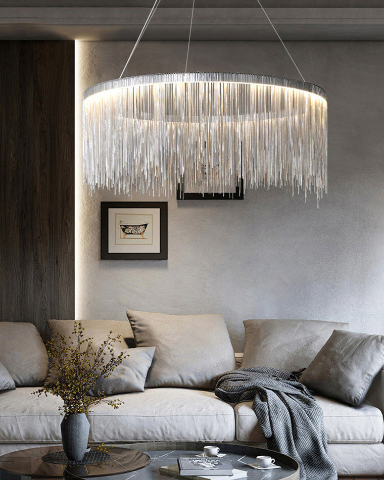 Side view of the silver chain chandelier above a gray sofa, showing how its shallow round profile adds drama without visually crowding the room.