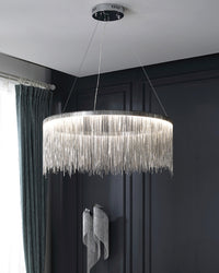 Silver chandelier glowing against dark wall panels, its reflective fringe transforming a simple ring of light into a sculptural evening centerpiece.